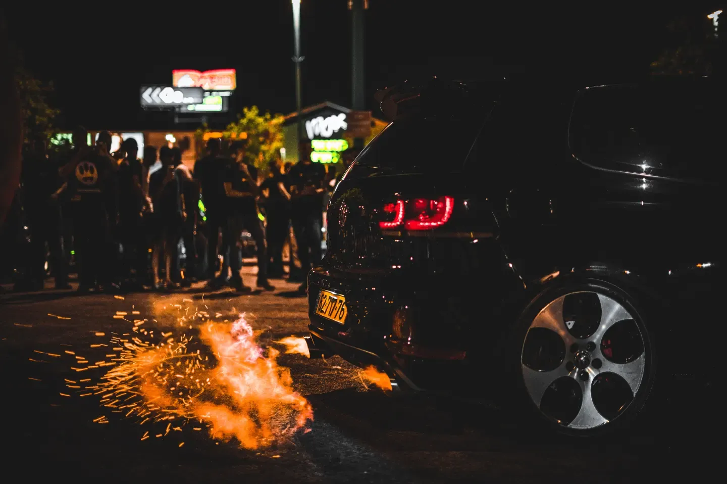 פולקסווגן גולף GTI שחורה מוציאה להבות מהאגזוז במפגש רכבים לילי