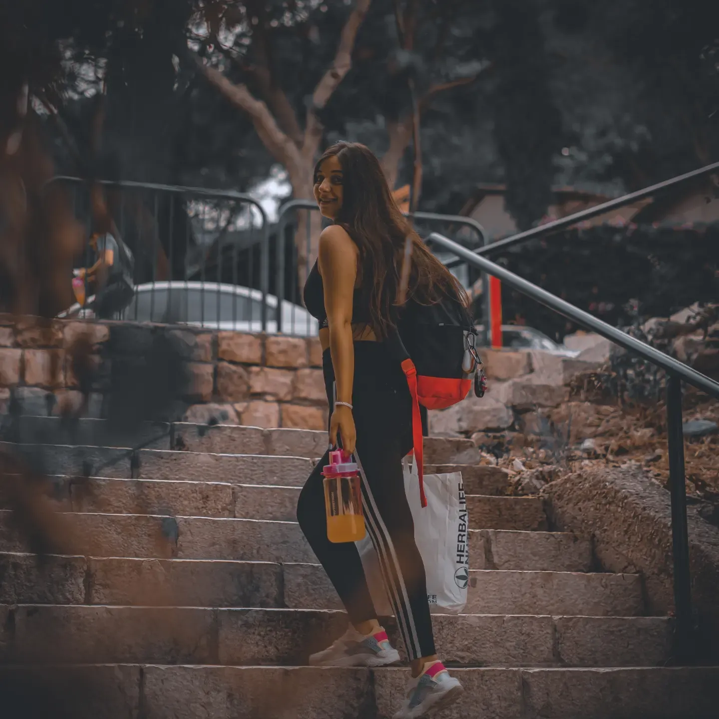 צילום לייפסטייל למותג ספורט — אישה בבגדי אימון על מדרגות אבן עם בקבוק שתייה ותיק